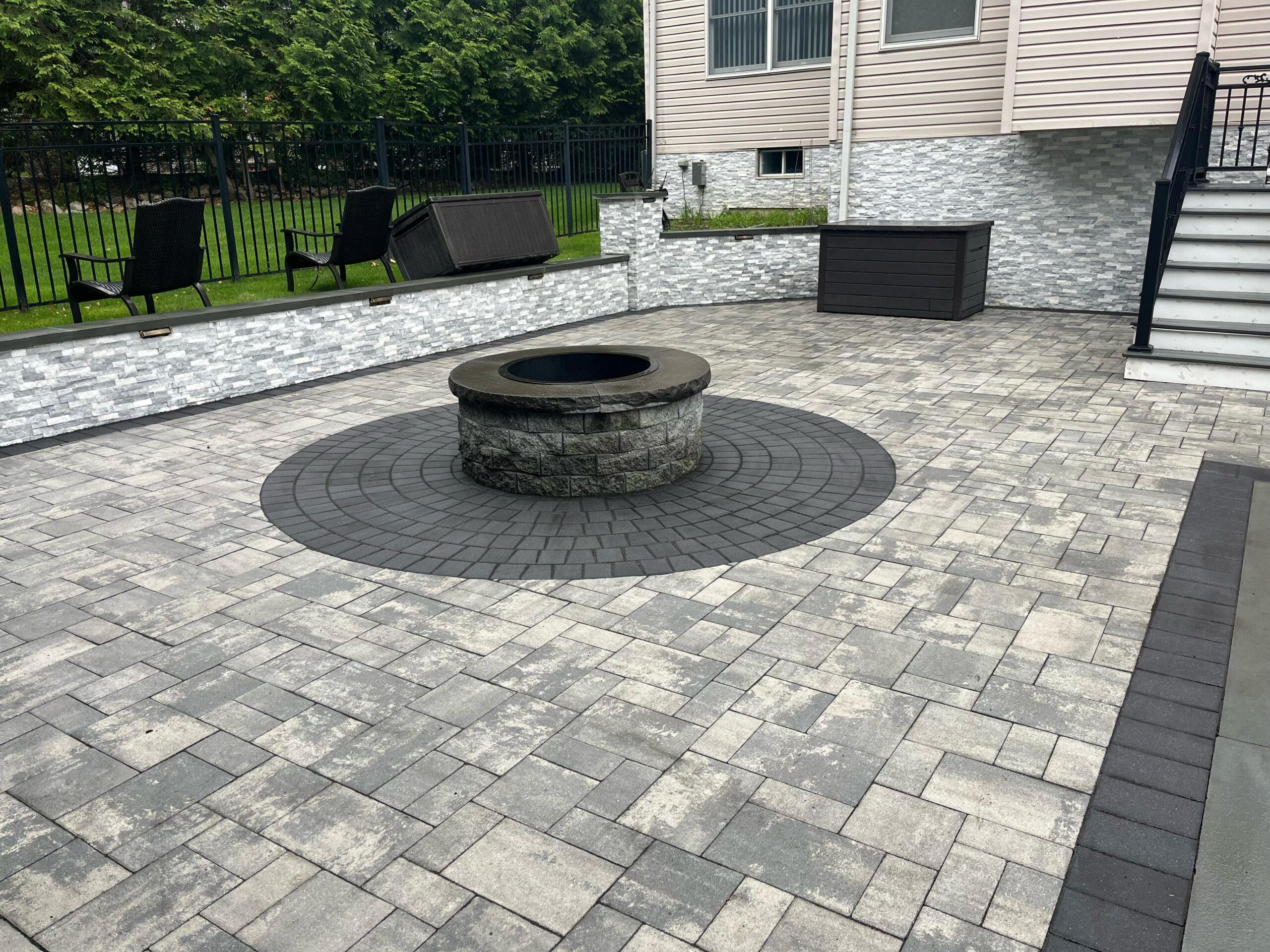 Backyard paver patio with circular fire pit and masonry wall in Wayne NJ