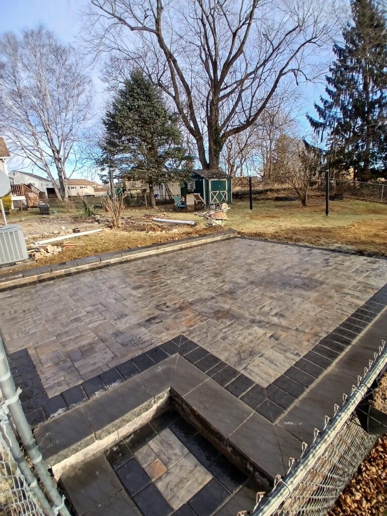 Backyard paver patio with masonry steps and dark border in Haledon NJ