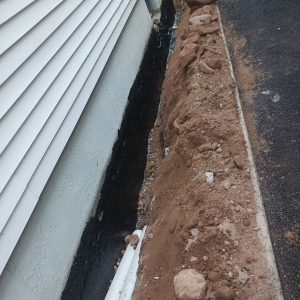 Exterior waterproofing membrane applied to a foundation wall