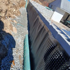 Foundation drainage board installed along an exterior wall