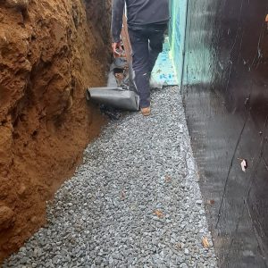 Drainage stone installed beside a waterproofed foundation wall